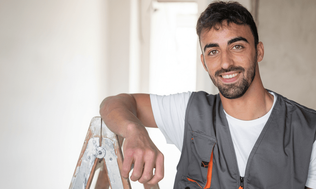 Profesional sonriendo apoyado en una escalera